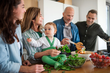 Happy multigeneration family indoors at home preparing vegetable salad. - Powered by Adobe