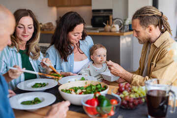 Happy multigeneration family indoors at home eating healthy lunch.