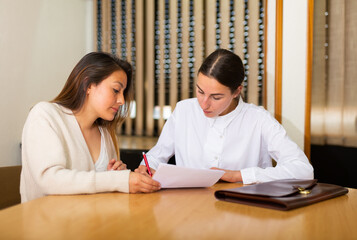 Obraz premium Two business woman in office interior filling up documents