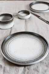 Empty pottery plate, sauceboats and cutlery on light background. Selective focus