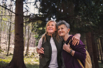 Senior women hikers outdoors walking in forest in nature, talking.