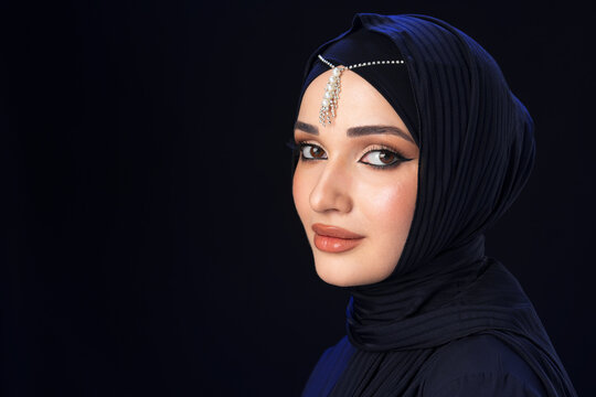 Portrait of a young muslim woman in hijab on black background