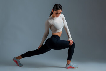 Girl performing lunges with body twists on grey background