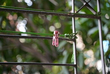 A pink cloths hanging pin on a meatal bar and in the balcony