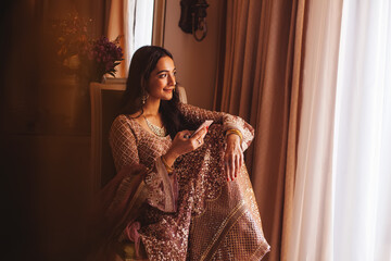 Rich beautiful Indian woman in luxury ethnic clothes using her phone in a 5 star hotel room....