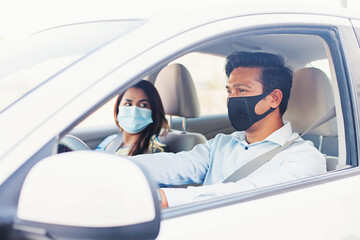 Indian couple in protective face masks riding in a car