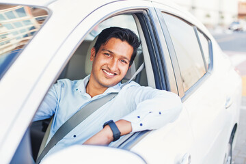 Young handsome Indian man proudly driving his own car
