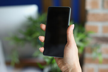 Black modern smartphone in female hand in office