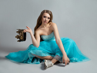 Modern princess, beauty in a crown and a lush blue dress and sneakers,