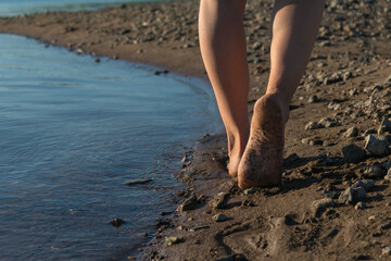 a girl walks along the beach, on fine sand, walk on the sand with her feet, heel. stop
