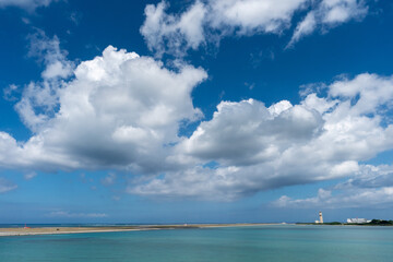 Fototapeta na wymiar 青い空に浮かぶ大きな綿雲と青い海の向こうに見える飛行場