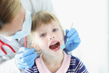 Dentist conducts medical examination of teeth of little girl