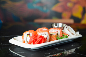 California or Philadelphia sushi rolls set served on a white tray over black background. Japanese cuisine concept