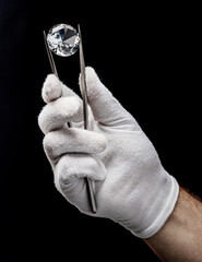 Large gemstone in jeweler's hand close up. Gem identifying and evaluating process.