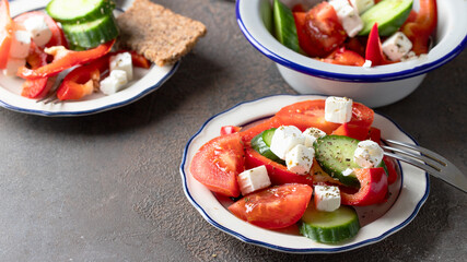 Greek salad with tomatoes, sweet pepper, cucumbers, and feta cheese in the plates on the restaurante table
