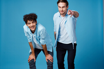 curly-haired guy in a blue shirt leaned forward and a blond man on a blue background friends