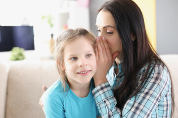 Mom whispers secret in the little girl ear