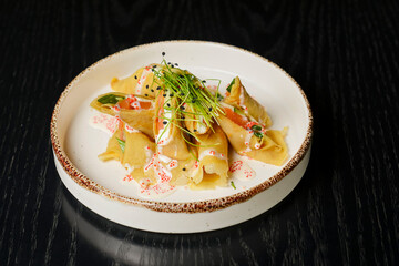 Fresh salmon and cream cheese crepes served in a white plate on a wooden table in restaurant or diner.