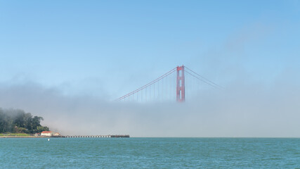Fototapeta premium San Francisco, USA - August 2019: Golden Gate Bridge under fog, with one tower visible. The Golden Gate Bridge is a suspension bridge spanning the Golden Gate.