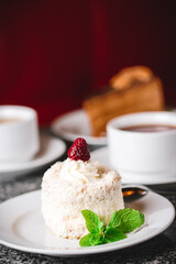 Coconut cake on a white plate with other food on the background.