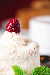 Coconut cake on a white plate with other food on the background.
