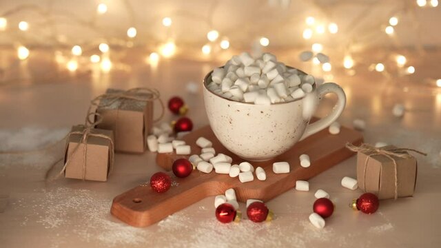 Marshmallows dropping cup with delicious hot chocolate cocoa drink.  Lights are on in the background. Slow motion. 