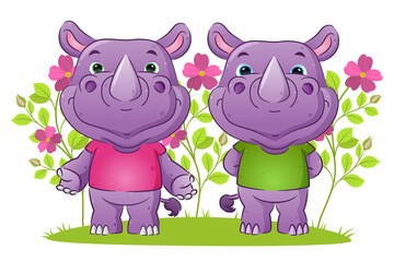 The couple of friendly rhino in the welcoming posing in the garden full of the flowers