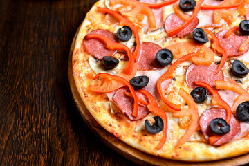 Simple pizza with mozzarella , olives and sweet pepper over dark rustic wooden background.
