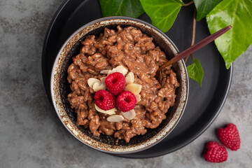 Chocolate rice porridge with raspberries and almonds. Top view.