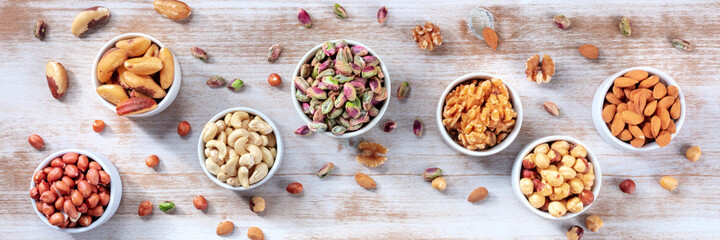 Nuts variety panorama, shot from the top on a rustic wooden background. Cashews, pistachios, walnuts and other nuts