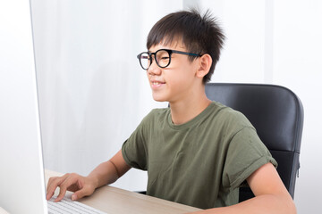 Young Asian preteen boy using computer at home for podcast, gaming, online education, learning remotely, homeschooling