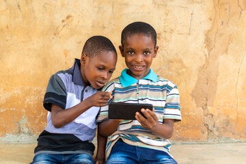 two african children feeling excited about they are doing with their cellphone
