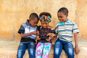 three africa children pointing to what they saw on their cellphone
