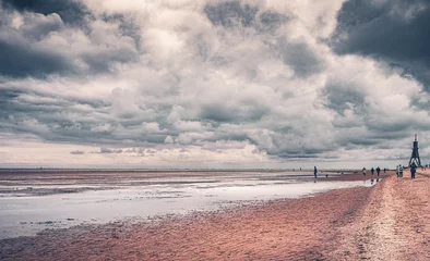 Deurstickers Strand von Cuxhaven an der deutschen Nordseeküste bei Ebbe mit dem Wahrzeichen der Kugelbake als Seezeichen. Einsamkeit bei dramatischem Himmel und einem surrealen Wolkenband © Jakob