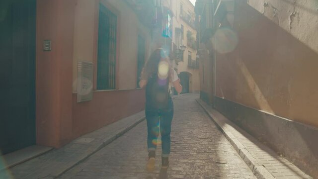Cinematic wanderlust shot of young woman on walk explore new city street. Sun flares in lens, happy and excited female tourist discovers new destination location