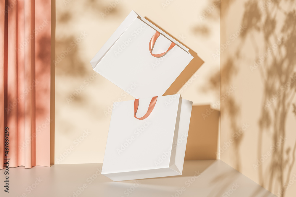 Poster two white paper bags with pink handles floating in the air on a beige background with curtains. mock