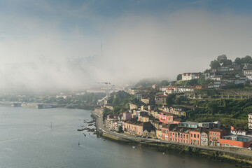 Summer morning view above beautiful Porto city from Portugal. Foggy cityscape in the start of a sunny day. Landmarks from Europe. A place to travel.