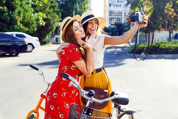 Two young pretty stylish girls posing near bright retro hipster bicycles