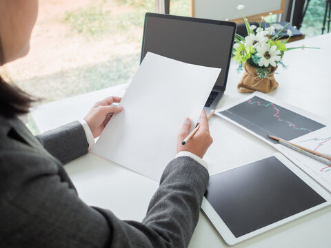 A businesswoman holding empty white papper, in an office in the afternoon.  Use technology to do banking, planing financial, Statistical Analysis, investment and marketing plans.