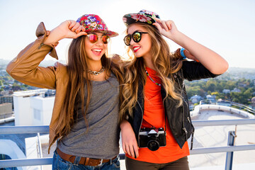 Outdoor lifestyle portrait of two best fiends sisters girls posing on the roof