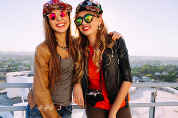 Outdoor lifestyle portrait of two best fiends sisters girls posing on the roof