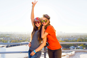 Outdoor lifestyle portrait of two best fiends sisters girls posing on the roof