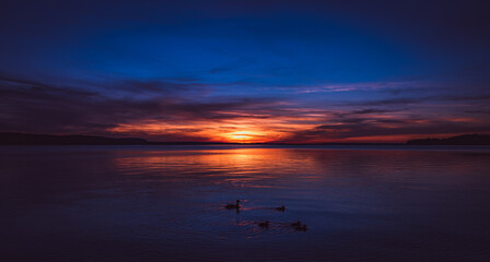 Sonnenuntergang im Sommer an einem großen, spiegelglattem See in wunderschöner, stiller...