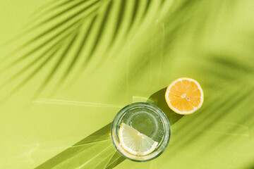 lemon water and palm tree shadow on green background with shadows