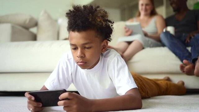 African boy playing on smartphone against background of parents with white tablet Spbd.