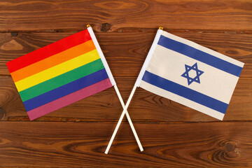 Rainbow flag LGBT and flag of Israel on brown wood planks background. LGBT Pride Month. LGBTQ. LGBTQIA. Close Up. Top view