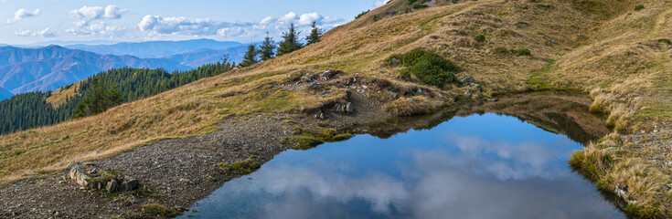 Small picturesque lake with clouds reflections at the  Strymba Mount. Beautiful autumn day in Carpathian Mountains near Kolochava village, Transcarpathia, Ukraine.