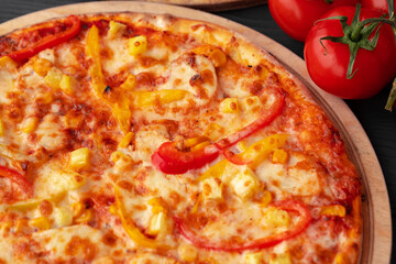 Close up of freshly baked pizza on black wooden table