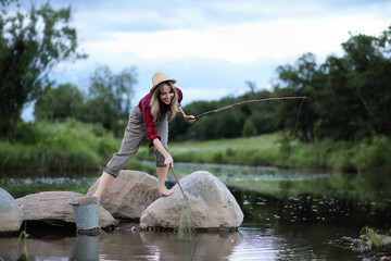 Girl by the river with a fishing rod