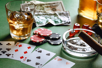 Glass of whiskey, cigar, playing cards and chips on green background